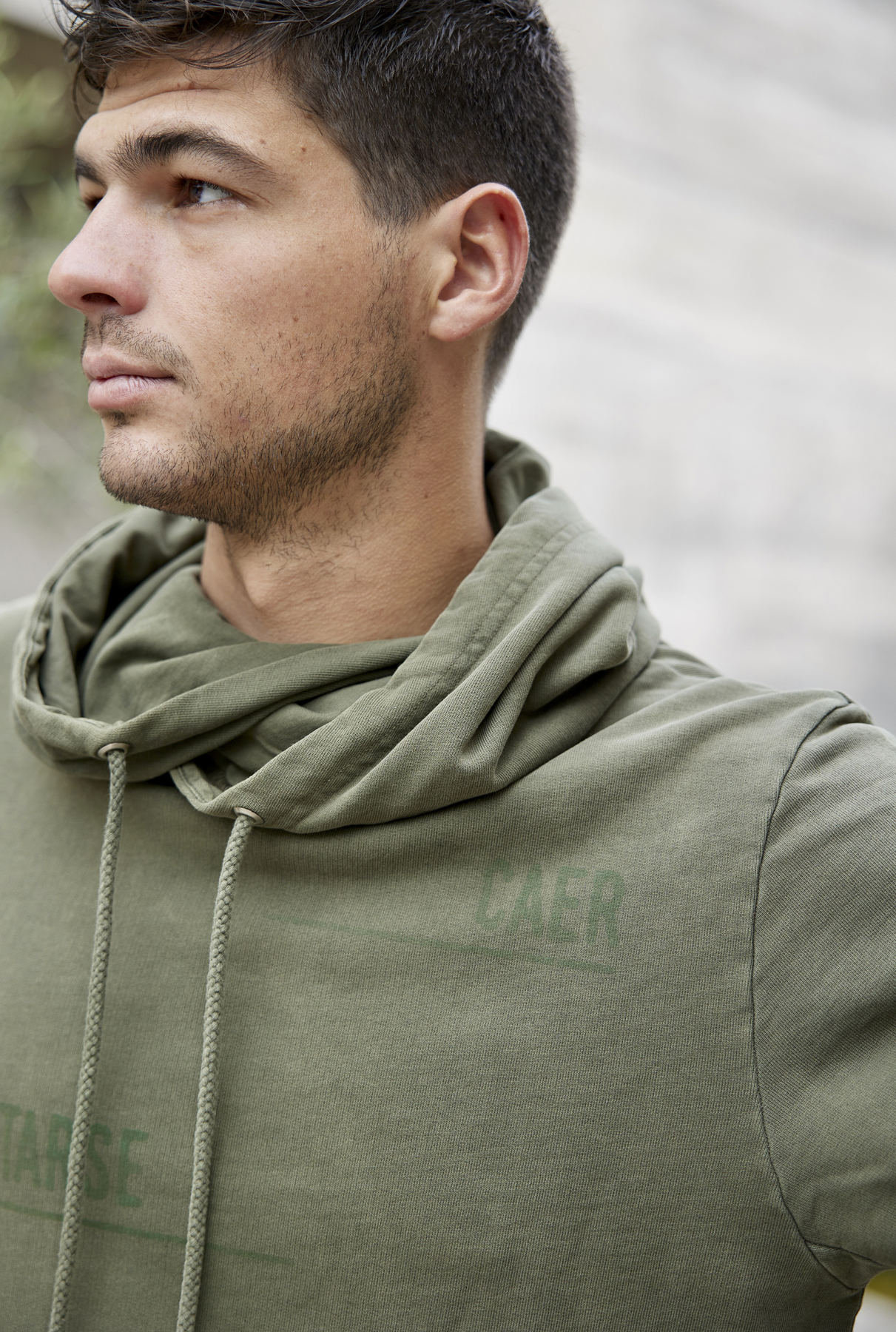 Polerón Millex Verde Oliva con cuello doble alto y capucha ajustable. Diseño en el frente que dice "caer levantarse siempre" en secciones. Fabricado con algodón de calidad.