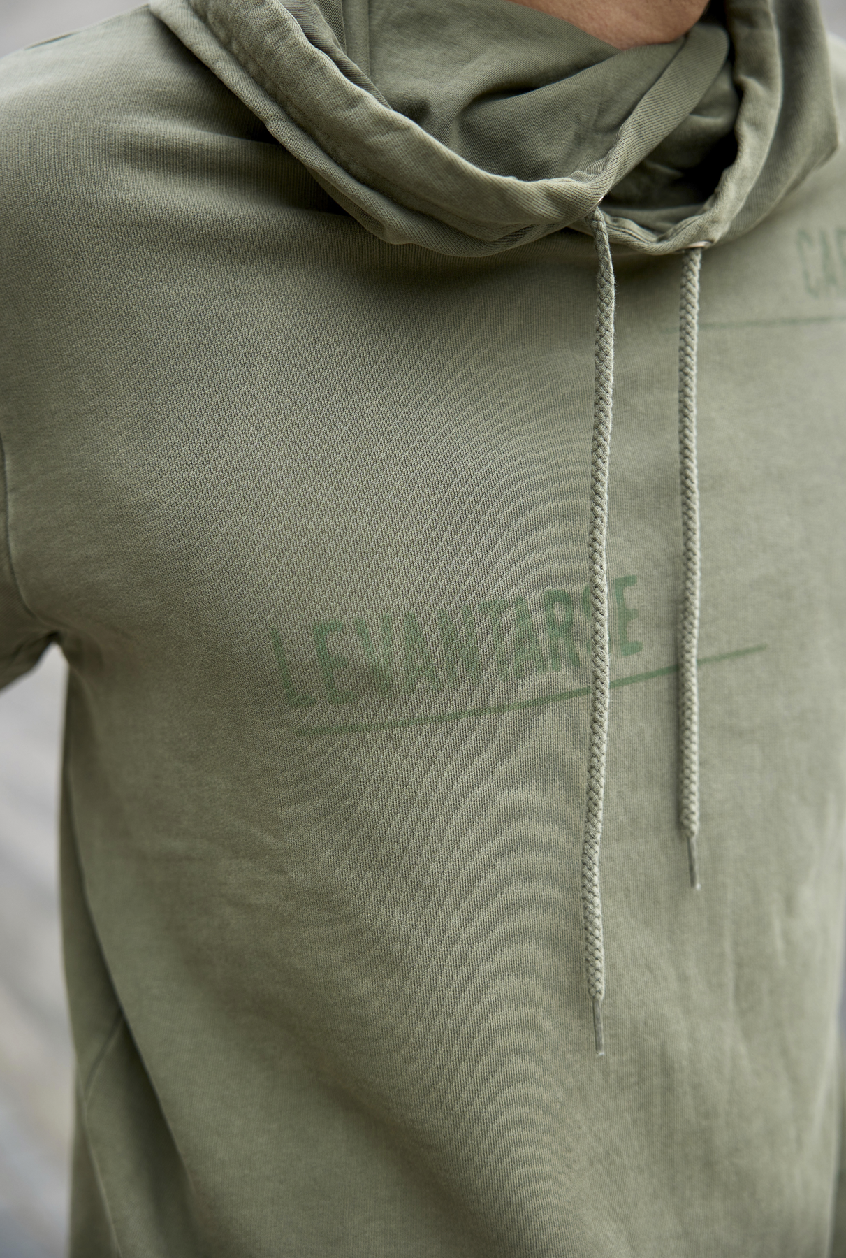 Polerón Millex Verde Oliva con cuello doble alto y capucha ajustable. Diseño en el frente que dice "caer levantarse siempre" en secciones. Fabricado con algodón de calidad.