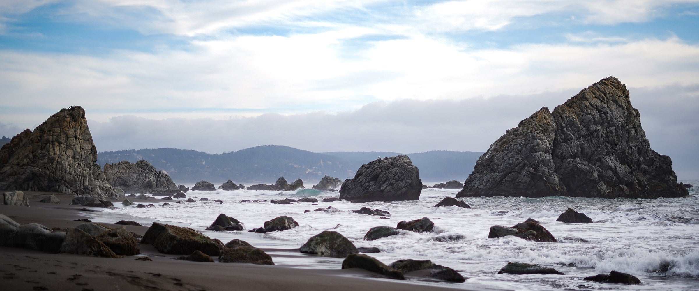 Farellon de roca y playa de arena negra en la costa de Chile