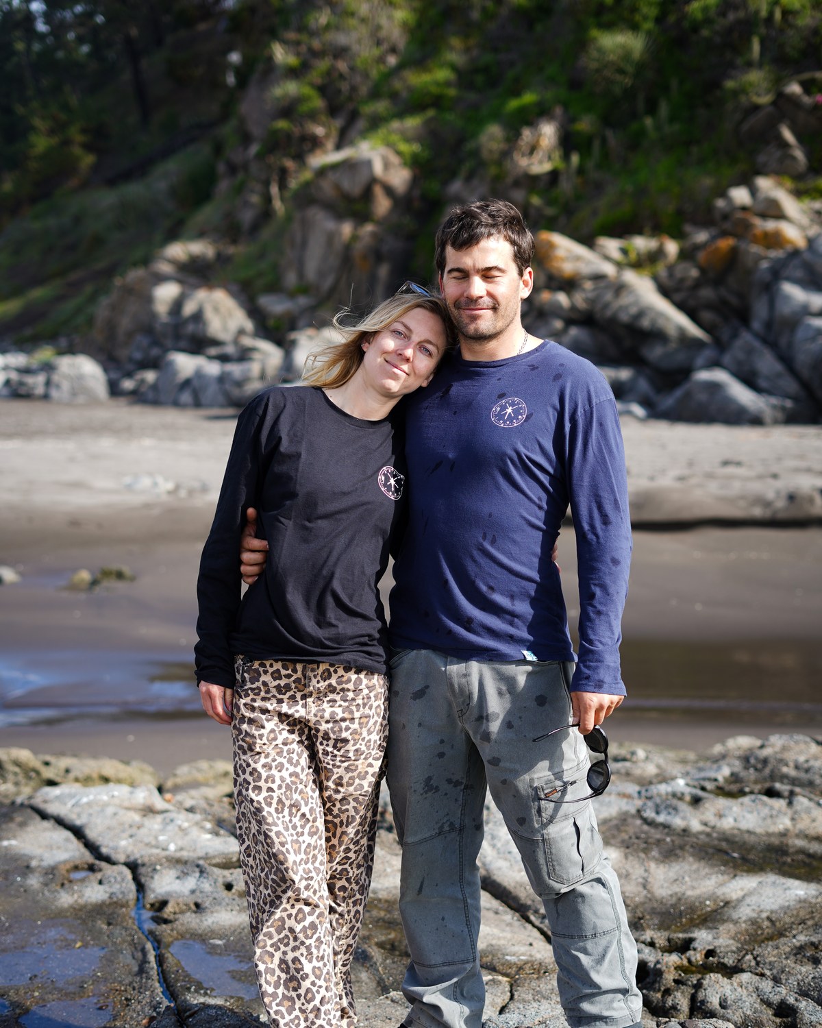 Pareja con poleras COA en la costa, version vertical para movil