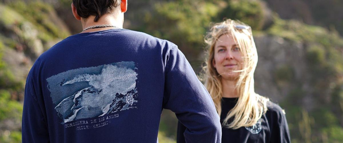 Pareja con poleras COA en la costa, ella mirando a camara