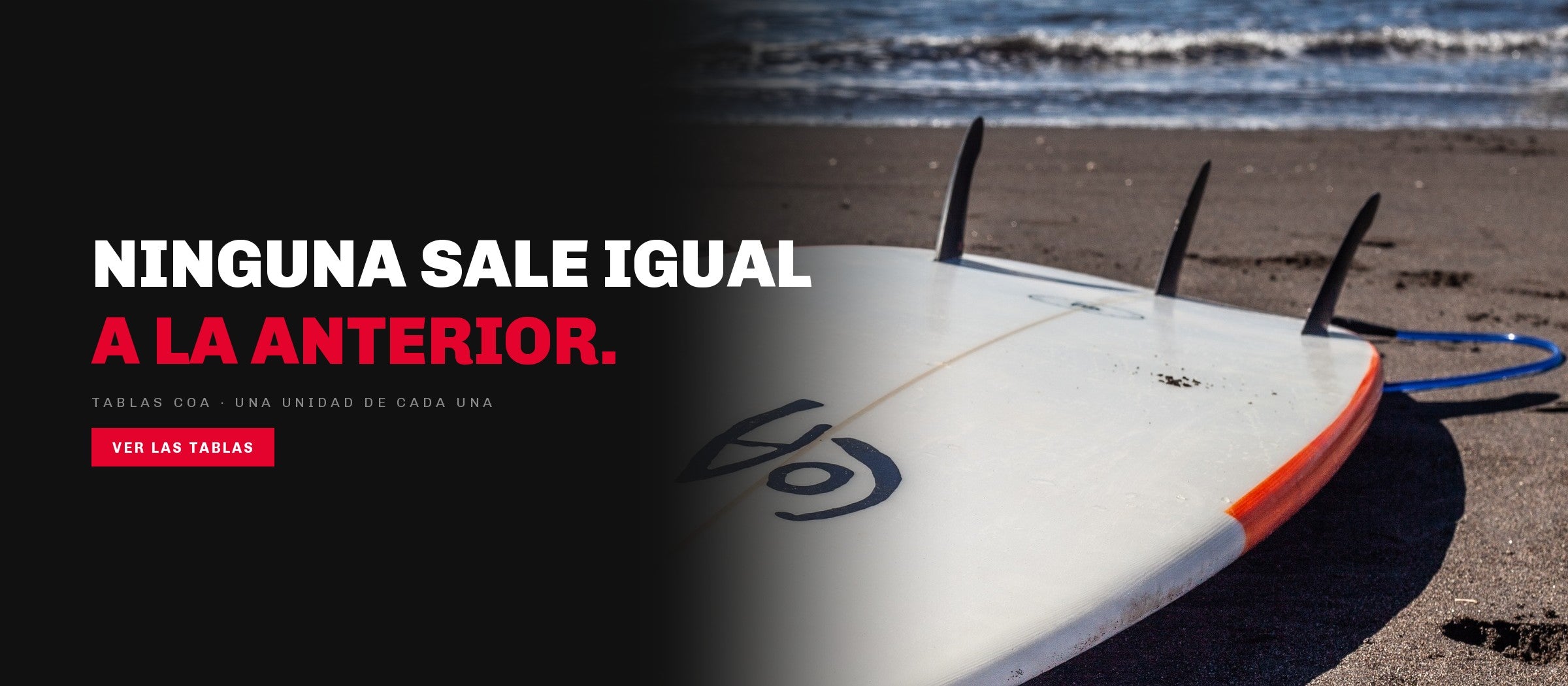 Tabla de surf COA sobre la arena negra con la ola rompiendo detras