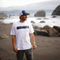 Polera Cicatriz blanca de COA caminando en la playa de arena negra