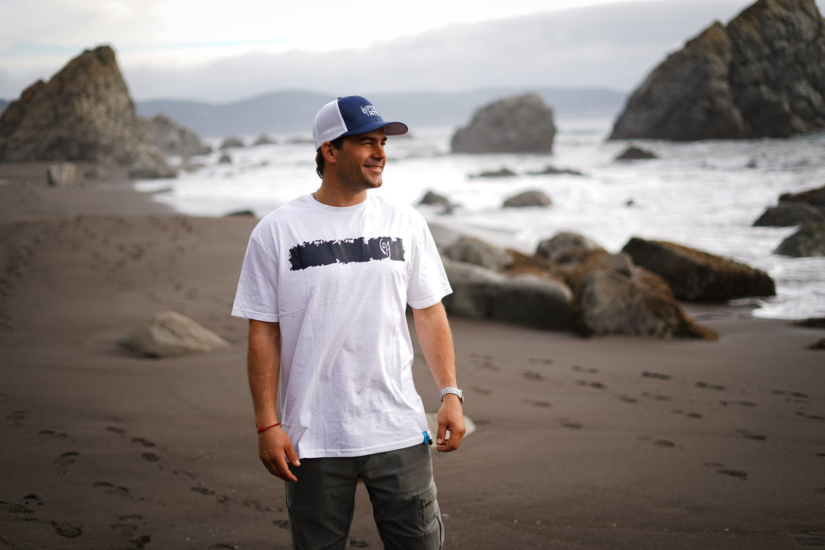 Polera Cicatriz blanca de COA caminando en la playa de arena negra