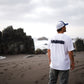 Polera Cicatriz blanca de COA de espaldas frente al mar